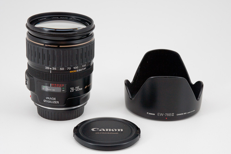 Canon EF 28-135mm F3.5-5.6 IS USM Side View showing zoom and focus scale, model name inscriptions and EW-78BII lens hood