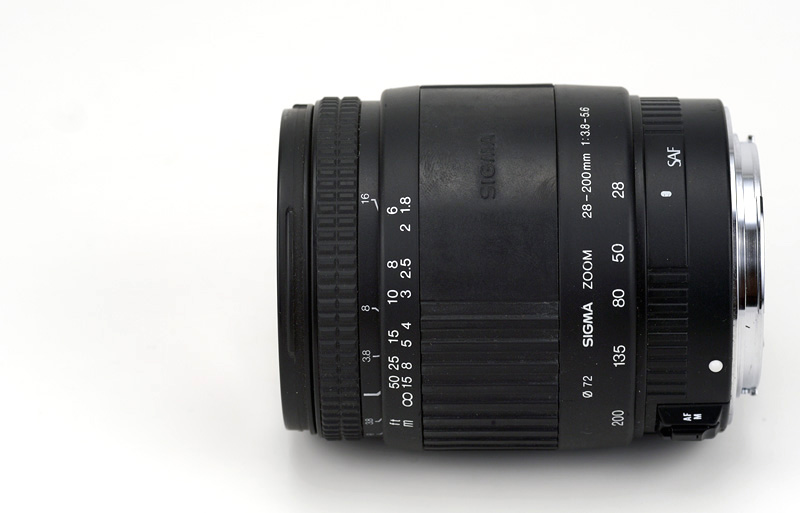 Sigma SAF 28-200mm F3.8-5.6 for Canon EF Side View showing model name inscription, zoom and focusing scales, filter size and SAF logo position